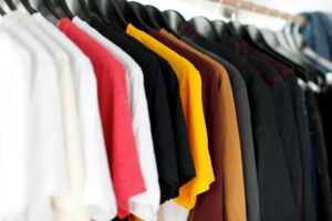A row of colorful t-shirts hanging on a clothing rack.
